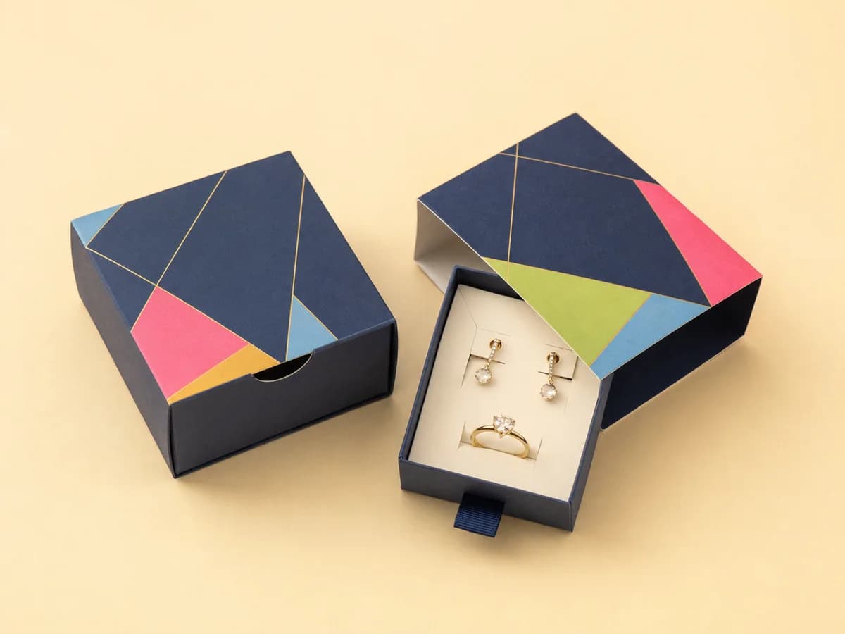 Navy geometric drawer sleeve jewellery box sliding open to reveal an earring and ring set